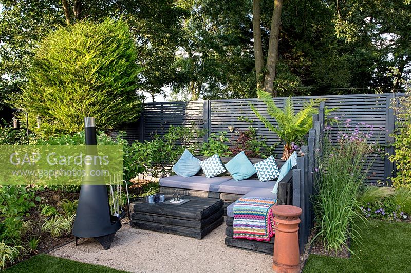 Jardin londonien contemporain avec clôture peinte en gris. Paravent en bois - Coin salon inférieur avec fleur de Chimenea Purple est Verbena bonariensis Tree Fern - Dicksonia Antarctica