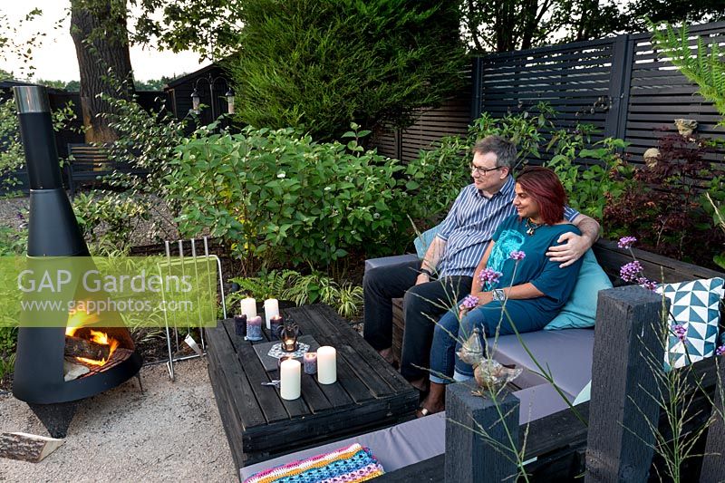Jardin de Londres contemporain dans la lumière du soir Mamta et Allan Mertner assis dans le jardin par chimenea