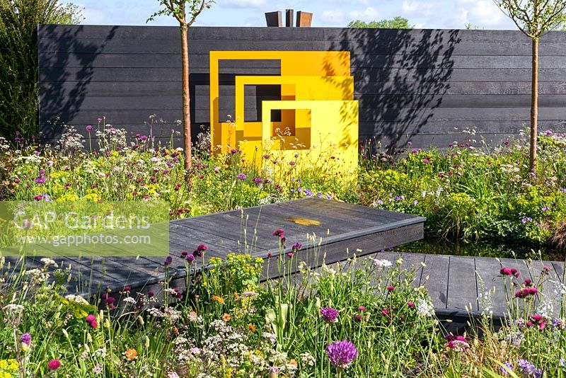 Panneaux sculpturaux en acier jaune avec clôture noire et plantation de style pré. 'Urban Oasis', RHS Malvern Spring Festival 2018.