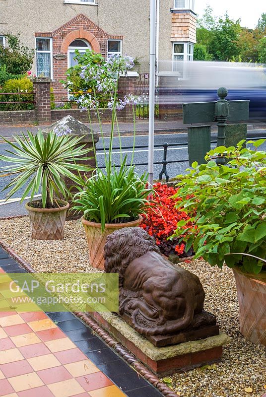 Jardin avant avec chemin carrelé et statue de lion. Le jardin secret de Serles House, Wimborne, Dorset, UK