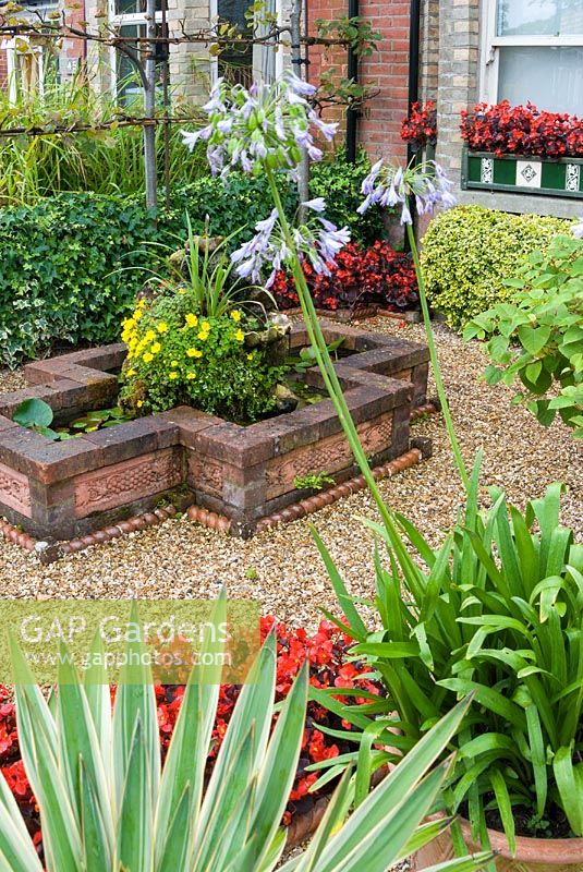 Jardin avant gravillonné avec plantes en pot et étang surélevé. Le jardin secret de Serles House, Dorset, UK.