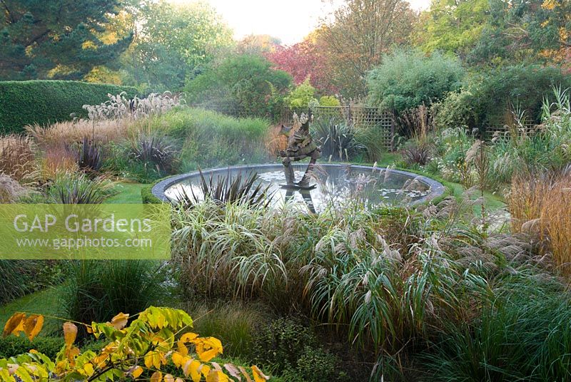 Jardin du dragon avec étang circulaire central avec sculpture de dragon. Knoll Gardens, nr Wimborne, Dorset, Royaume-Uni