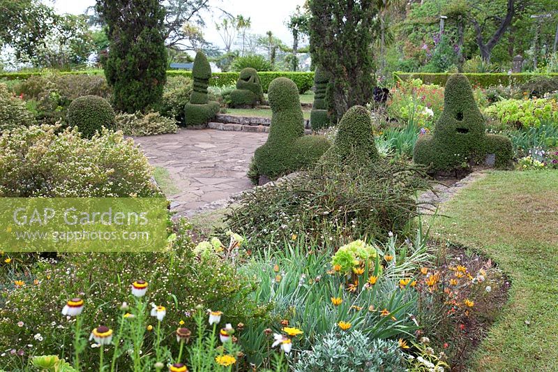 Vue sur le jardin pavé en contrebas avec des formes topiaires inhabituelles