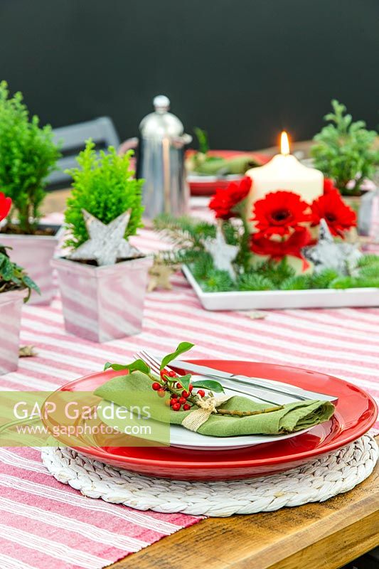 Cadre de table festif rouge, blanc et vert, avec vue sur la pièce maîtresse de l'arrangement des bougies.