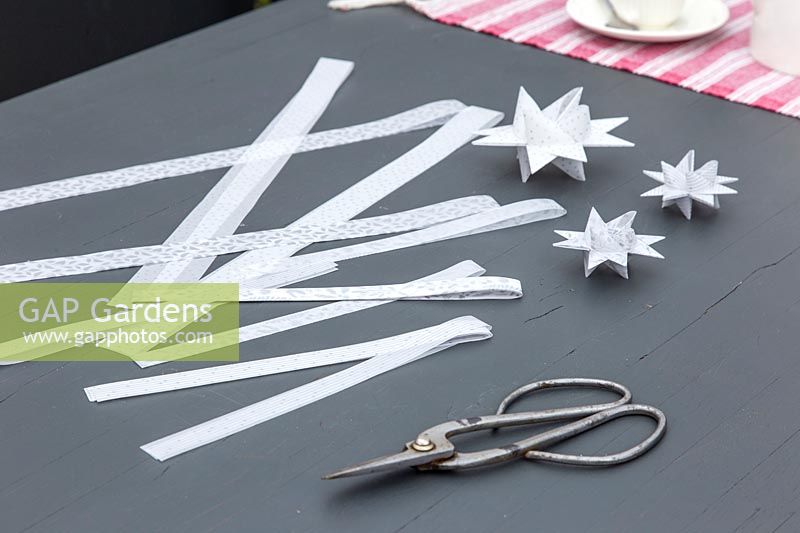 Matériaux et outils pour créer des étoiles en papier 3D décoratives.