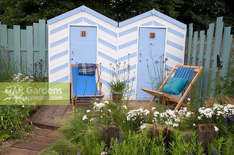 Cabines de plage bleues et blanches et chaises en bois bordées de plantations côtières bleues et blanches. Southend Council 'By The Sea' garden at RHS Hampton Court Flower Show, Londres, 2017.