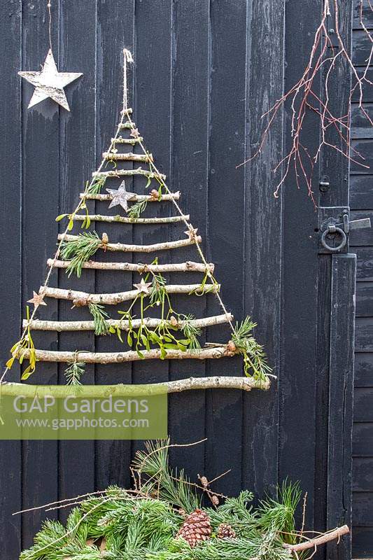 Sapin de Noël suspendu décoratif, fait de bâtons et recouvert d'étoiles de pin, de gui et d'écorce.