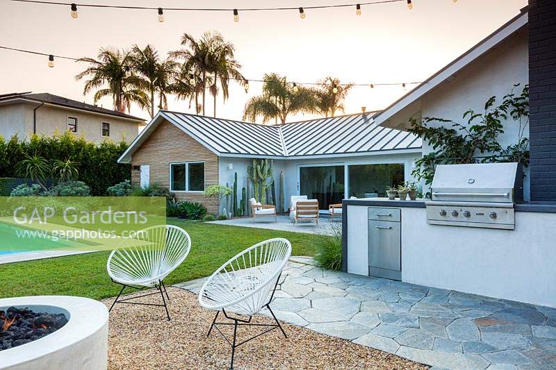 Vue sur le jardin avec des guirlandes lumineuses pour la piscine et le coin salon extérieur. Jardin conçu par Falling Waters Landscape, inc Ryan Prange, New Port Beach, Californie, USA.