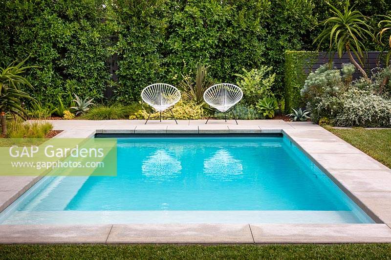 Une paire de chaises de jardin vintage Acapulco au bord de la piscine dans le jardin californien. Conçu par Falling Waters Landscape, inc Ryan Prange, New Port Beach, Californie, États-Unis.