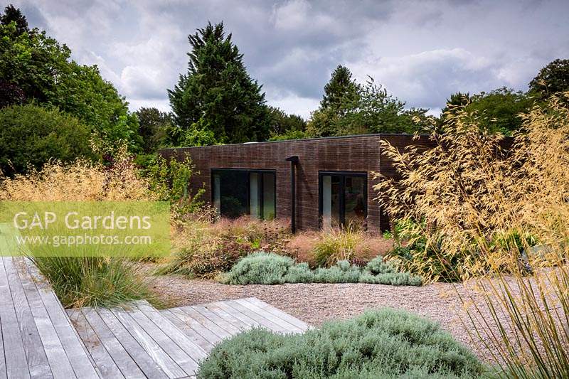 La maison et les parterres mixtes environnants dans un jardin de campagne contemporain près de Winchester, Hants, Royaume-Uni. Conception du jardin Elks-Smith.