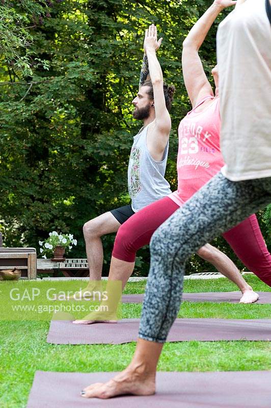 Personnes pratiquant le yoga dans le jardin.