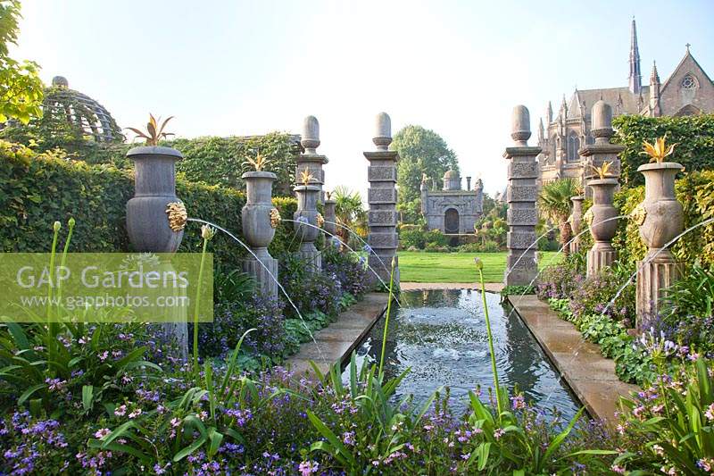 Fontaines à l'italienne dans le jardin du collectionneur Earl, à côté de la piscine avec Agapanthus en fleurs, Lobelia et Scaevola avec la cathédrale au-delà. Château d'Arundel, Sussex, UK.