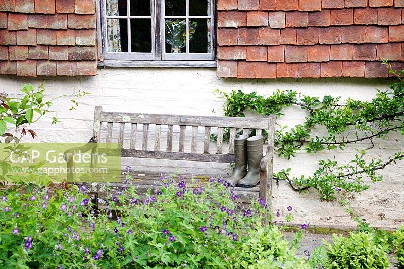 Bottes en caoutchouc sur un vieux banc en bois à l'extérieur du chalet. Copyhold Hollow, Sussex, Royaume-Uni.