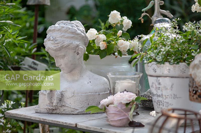 Collection d'articles vintage sur le thème blanc sur une table. Il s'agit notamment d'un buste de tête de femme et de plantes en pot à fleurs blanches.
