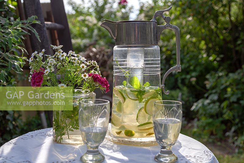 Deux verres d'eau citronnée avec bouquet de fleurs, mis sur table dans un jardin