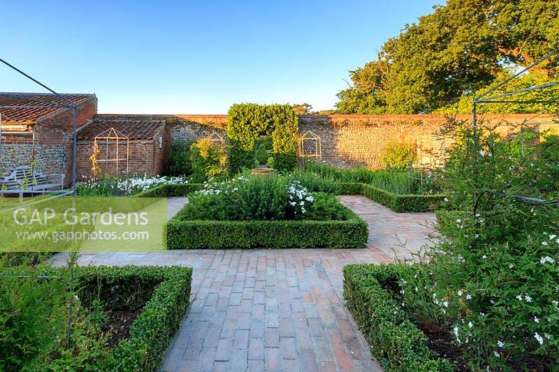 Le jardin blanc, entouré de murs en brique patinée et en silex. Walcott House, Norfolk, Royaume-Uni.