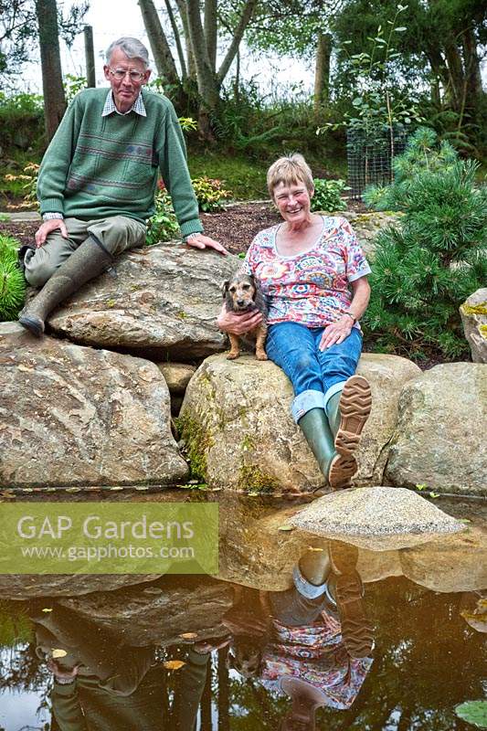 Margaret et Iain Gimblett avec chien de compagnie assis sur des rochers au bord de l'étang.