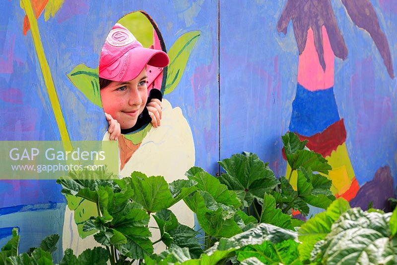 'O Beoley-wan-Kenobi 'garden show scolaire, un élève pose pour la caméra dans le trou de tête du personnage de Star Wars Yoda, peint sur le mur arrière du jardin