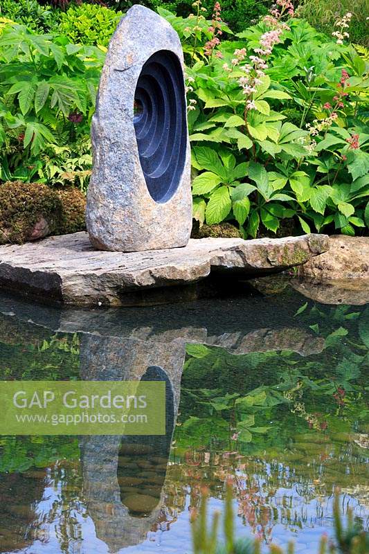 Vue de la sculpture en pierre focale sur les rochers reflétée dans une piscine. 'At One With ... A Meditation Garden', conçu par Peter Dowle, RHS Malvern Spring Festival, 2017.