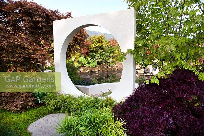 Vue à travers une ouverture circulaire en sculpure carrée dans le jardin d'exposition 'At One With ... A Meditation Garden '