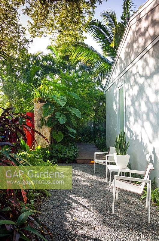 Chaises et table sur chemin de gravier dans un jardin tropical. Résidence Von Phister, Key West, Floride, USA. Conception de jardin par Craig Reynolds.