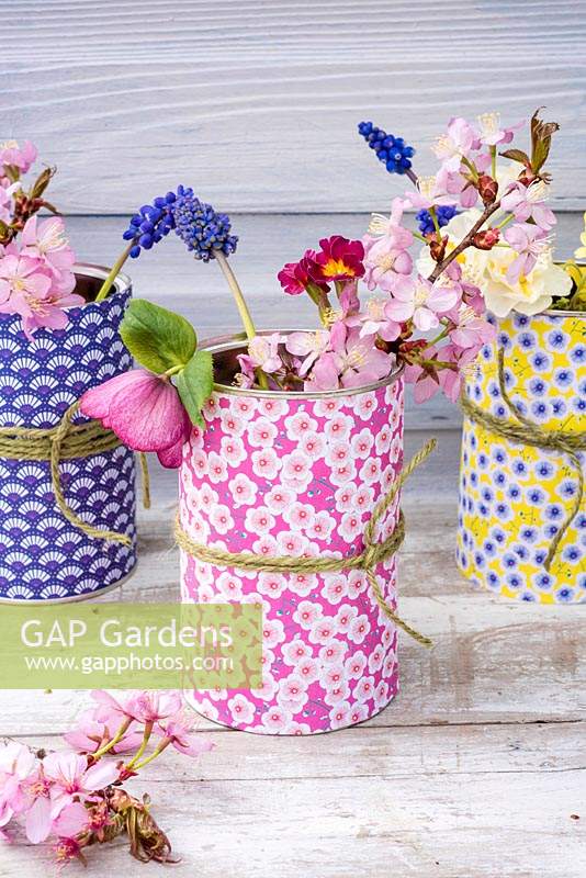 Boîtes de conserve recouvertes de papier origami utilisées comme vases à fleurs pour les fleurs de printemps.