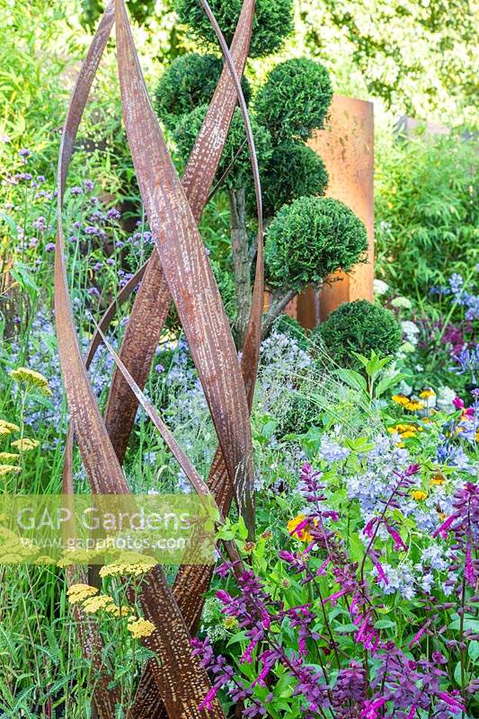 Sculpture de Simon Probyn parmi les fleurs avec un arbre taillé dans les nuages dans le jardin 'Brilliance in Bloom'