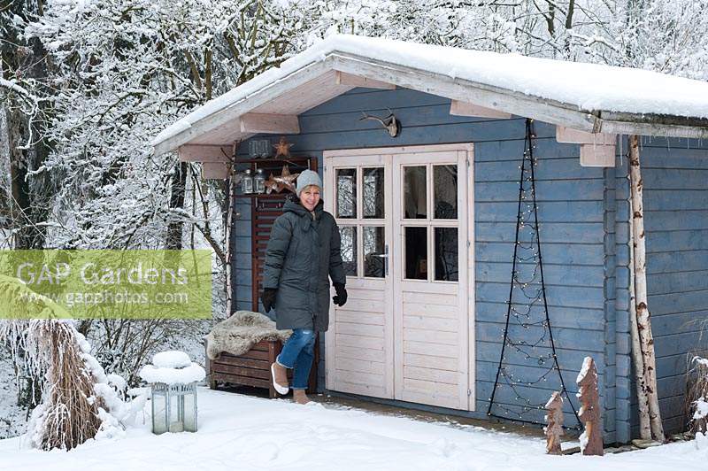 Une femme à l'extérieur du pavillon d'été bleu recouvert de neige en hiver.