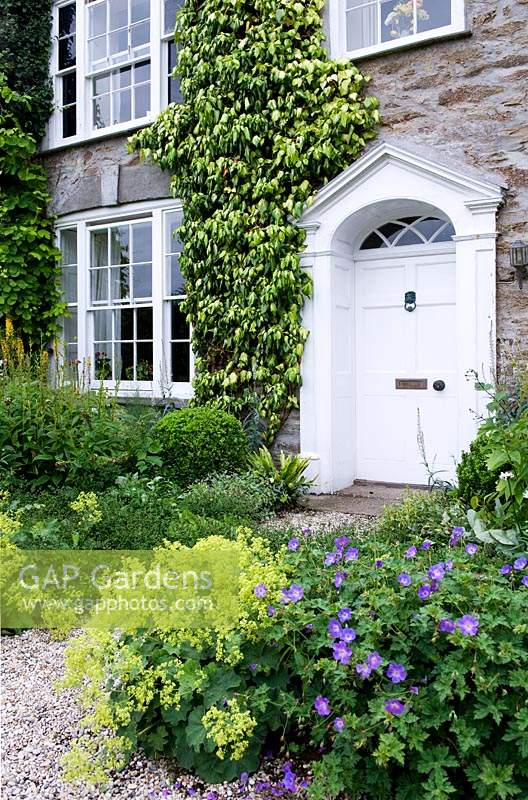 Porte d'entrée entourée de massifs de fleurs vivaces. Bosvigo House, Cornwall, Royaume-Uni.