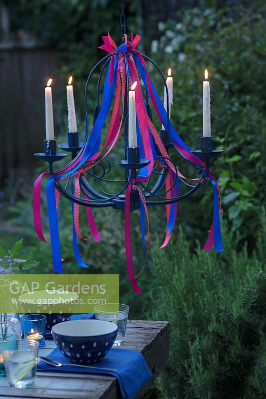 Un lustre en ruban sur une table à manger au crépuscule avec toutes les bougies allumées.