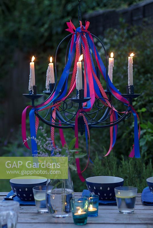 Lustre ruban avec des bougies allumées, suspendu au-dessus d'une table à manger au crépuscule.