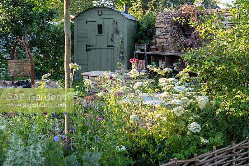 Un jardin champêtre romantique planté principalement de plantes médicinales, une cabane de berger et une collection éclectique d'objets. Le jardin Naturecraft, conçu par Pollyanna Wilkinson, RHS Hampton Court Palace Garden Festival, 2019.