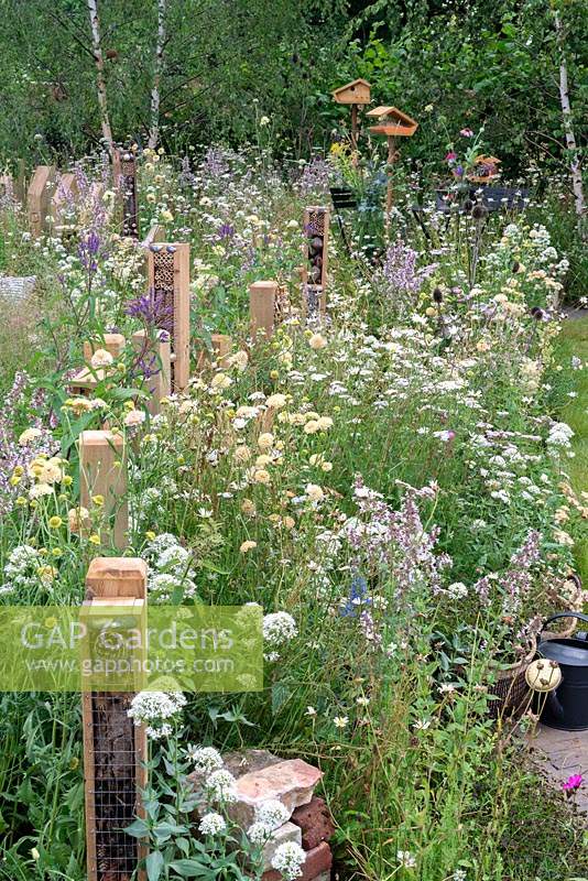Poteaux de clôture respectueux des insectes avec des hôtels d'insectes le long du parterre de fleurs vivaces. RHS Hampton Court Festival 2019.