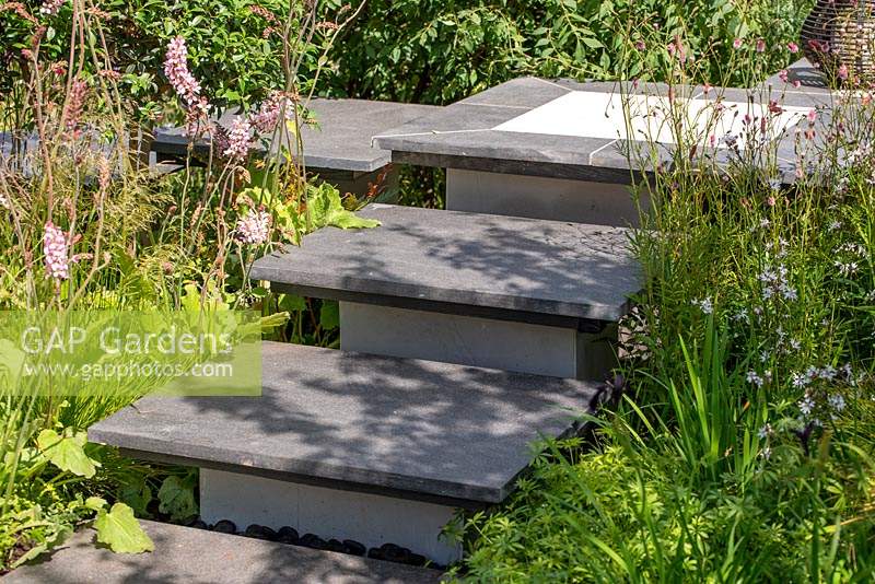 Des marches pavées mènent à travers des parterres de plantes herbacées. RHS Hampton Court Palace Flower Festival 2019.