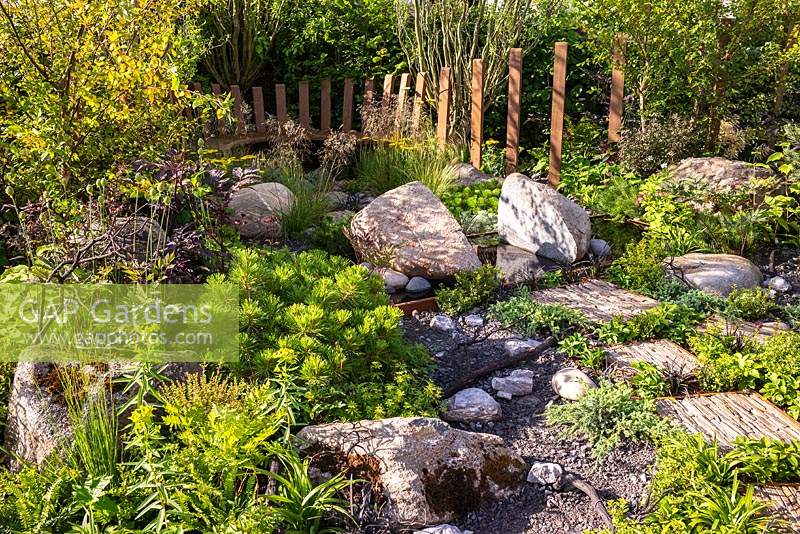 Utilisation de roches et de pierres naturelles, avec une plantation de feuillage vert. RHS Hampton Court Palace Garden Festival 2019. Commanditaires: Kebony, CED Stone, R and G Metal Products, William's Art and Design, Practicality Brown.