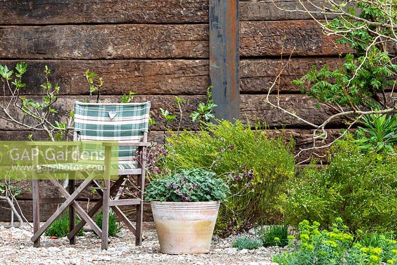 Mur en bois avec traverse en bois avec siège pliant en bois à proximité dans le jardin de la résilience au RHS Chelsea Flower Show 2019