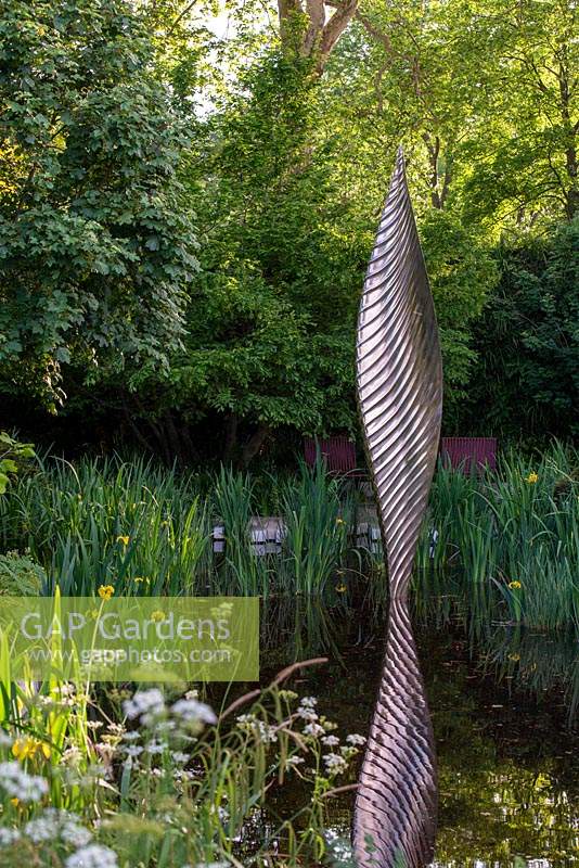 Éclat de bronze de David Harber situé dans une piscine entourée d'Iris pseudacorus et de plantations sauvages de Cow Parsley - The Savills and David Harber Garden, RHS Chelsea Flower Show 2019.