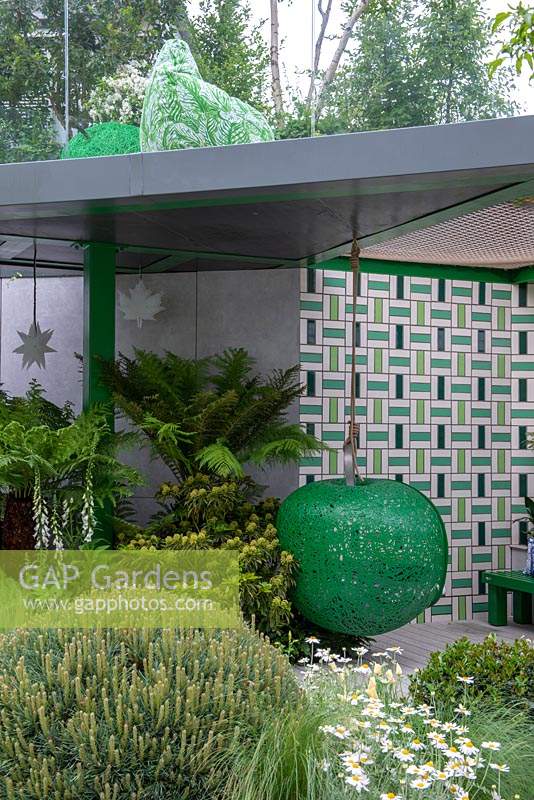 Siège suspendu en forme de pomme sous un pavillon avec Dicksonia antarctica - The Greenfingers Charity Garden, RHS Chelsea Flower Show, 2019.