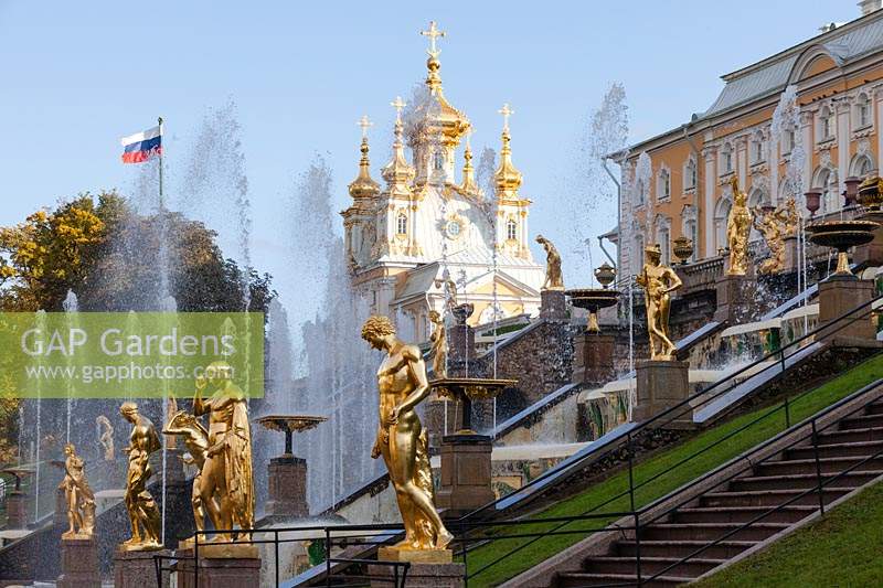 La Grande Cascade avec des fontaines et des statues peintes en or. Palais et drapeau de la Fédération de Russie