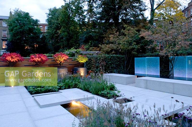 Vue sur le jardin de la ville moderne, avec des jardinières, éclairé par un éclairage contemporain au crépuscule