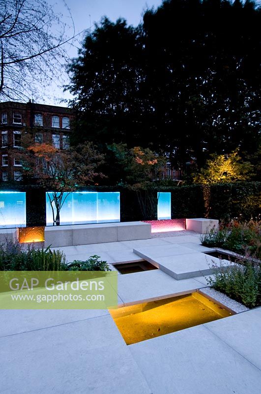 Vue sur le jardin de la ville moderne, avec dallage blanc et jardinières, éclairé par un éclairage contemporain au crépuscule