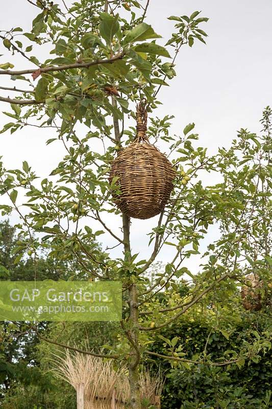 Le Jardin Qui Chante, The Singing Garden, Festival International des Jardins 2019, Domaine de Chaumont sur Loire, France. Pot rond en vannerie suspendu dans un arbre.