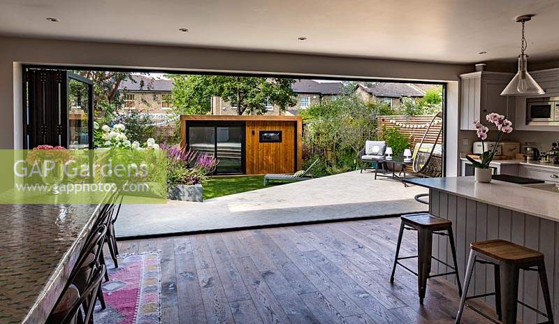 Une vue sur un jardin contemporain, avec salon de jardin, depuis la cuisine