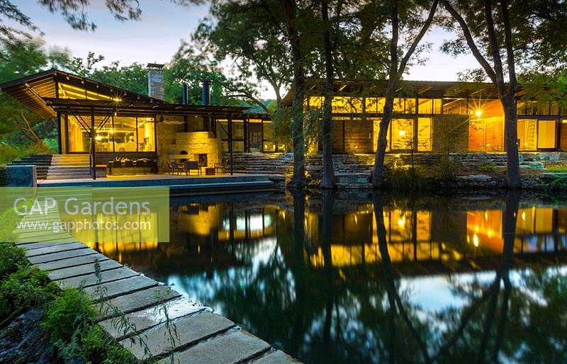 Vue crépusculaire de la piscine et des bâtiments à Mill Creek Ranch à Vanderpool, Texas conçu par Ten Eyck Landscape Inc, juillet.
