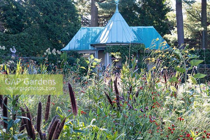 Pré fleuri à l'automne au jardin Chanticleer avec toit en métal turquoise de pool house en arrière-plan