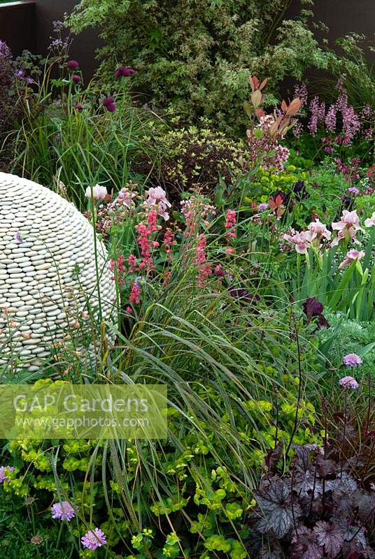 Plantation d'herbacées entourant une caractéristique sphérique faite de galets dans un parterre de jardin - RHS Malvern Spring Festival 2014