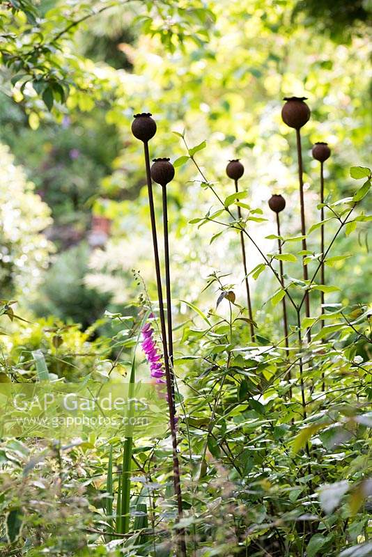 Graines de pavot en métal décoratives faites par Jason Thompson dans un parterre de fleurs à Ivy House, Cumwhitton en juillet