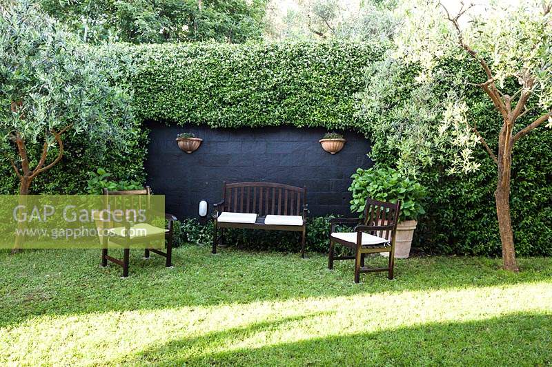 Espace détente avec banc et chaises dans le jardin avec pelouse