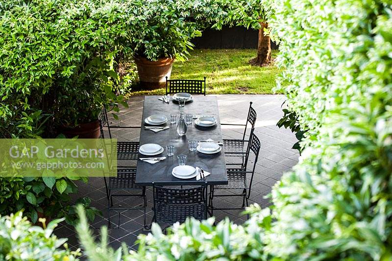 Table à manger et chaises sur patio carrelé noir.