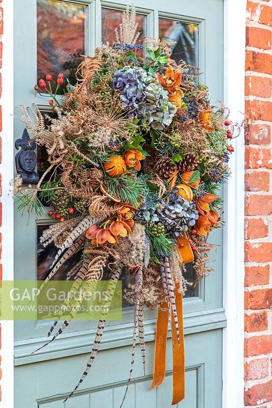 Couronne festive orange rustique, verte et bleue accrochée à la porte d'entrée de style stable